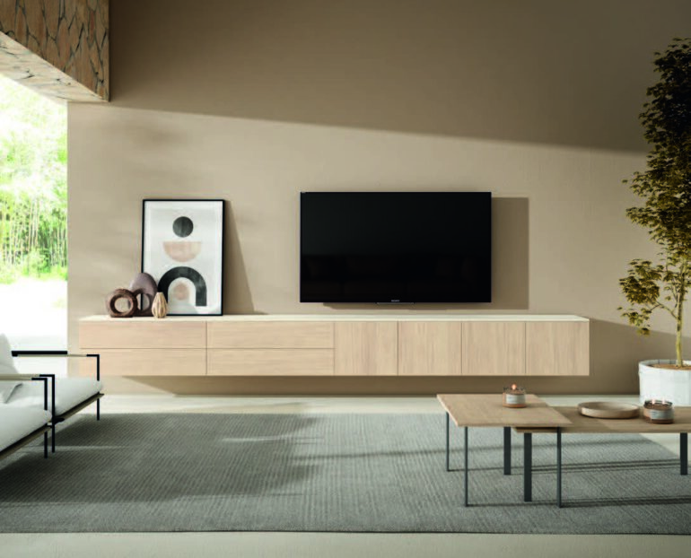 Modern living room: TV on a floating light-wood console with framed art and decorative objects nearby on a gray rug.