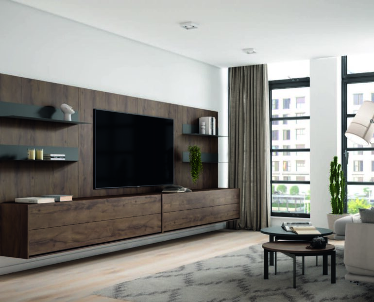 Modern living room with a dark wood entertainment wall, flat-screen TV, floating shelves, low cabinets, and a round coffee table next to a gray sofa.